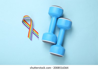 LGBT rainbow ribbon pride tape symbol and dumbbells on blue background. Sport and love concept. Top view. Flat lay