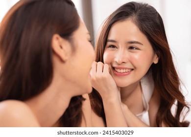 LGBTQ+ Asian couple laughing together at home. Affectionate young lesbian couple sharing a laugh while sitting on their bed at home. LGBTQ+ concept. - Powered by Shutterstock