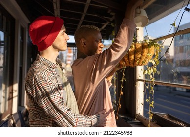 LGBTQ Couple Watering Plants On Their Porch.