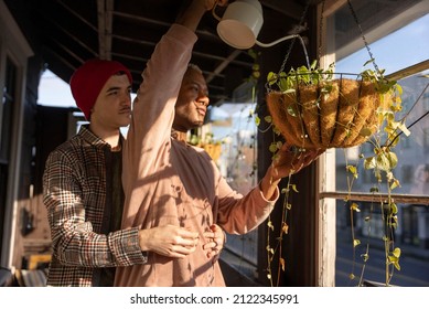 LGBTQ Couple Watering Plants On Their Porch.