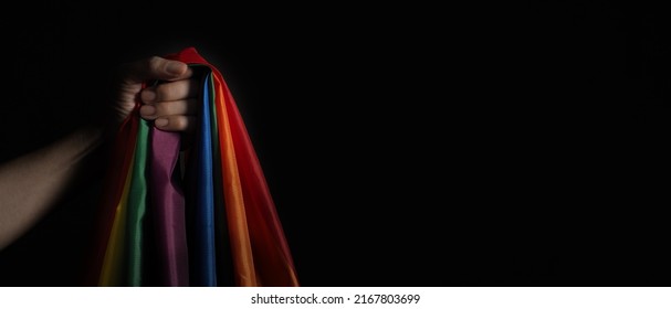 LGBTQ Pride Flag On Black Background. Lgbt Rainbow Flag In Gay Hand. Represent Symbol Of Freedom Peace Equality And Love And Respect  Diversity Of Sexuality. Lesbian Gay Bi Sexsual Transgender Queer.