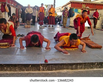    LHASA, TIBET-NOVEMBER 11: Pilgrims prayer and prostration in front of the Jokhang temple. This historic temple is the holiest site in Tibetan Buddhism. November 11, 2004 in Lhasa, Tibet