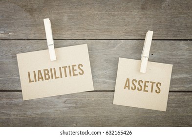 Liabilities or assets, business conceptual words with brown paper sheets or notes stick on a wooden background. Attached with paper clips or pin. - Shutterstock ID 632165426