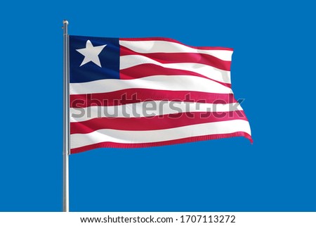 Liberia national flag waving in the wind on a deep blue sky. High quality fabric. International relations concept.