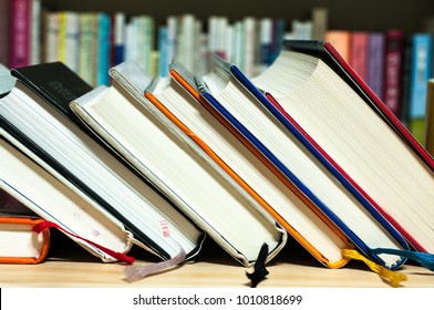 Library Books stacked on a wooden desk and books on a bookshelf. - Shutterstock ID 1010818699
