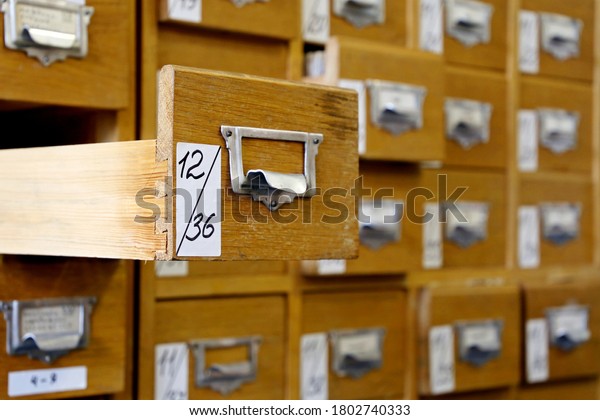Library catalogue cards\
in old wooden box. File archive, opened drawer with paper\
documents, database\
concept