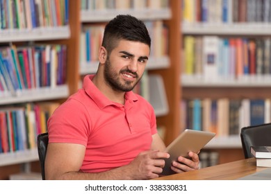 In The Library - Handsome Arabic Male Student With Laptop And Books Working In A High School - University Library - Shallow Depth Of Field - Shutterstock ID 338330831