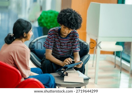 Library lounge study scene with students using digital device for discussion reflecting collaborative education academic focus learning lifestyle.