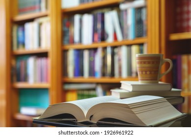 library with many books to read, arranged on shelves. Open book and cup close-up. Copy space. Background.