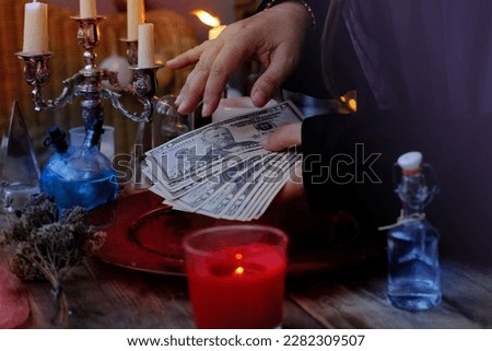 Librate with money, female hands of psychic doing witchcraft passes with dollars, esoteric Oracle performs ritual of removing spell of black magic, esoteric business, magic to increase income
