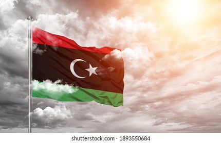Libya national flag cloth fabric on cloud background.