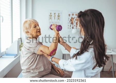 Licensed chiropractor examining senior woman's arm in office of modern well-equipped clinic. Professional physiotherapist helping female patient to cure health problems and recover after elbow injury