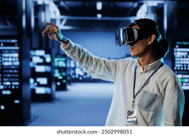 Licensed engineer in data center uses virtual reality to prevent system overload. Professional with VR goggles in server room ensuring enough network bandwidth for smooth operations - Powered by Shutterstock