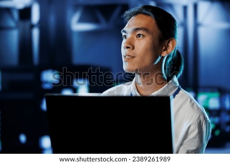 Licensed technician between server hub rows providing processing resources for businesses worldwide. Trained specialist fixing data center mainframes tasked with managing massive databases