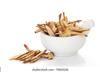 Licorice Root In A Porcelain Mortar With Pestle. Used In Traditional Chinese Herbal Medicine And For Culinary Purposes, Isolated Over White Background.