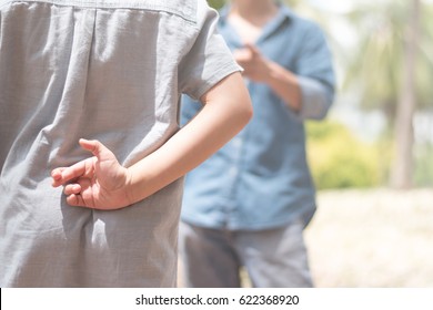 Lie kids concept.Liar female child hand crossing fingers behind back with father in front. lie and cheating, problem child. April Fools' Day - Shutterstock ID 622368920