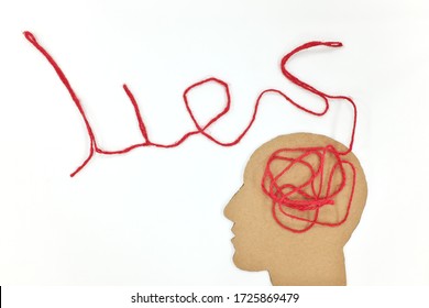 Lies, brainwashing and fake news concept. Human head profile silhouette with red yarn composed into word lies as brain gear.