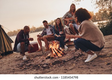 Life is awesome. Group of young people in casual wear smiling while enjoying beach party near the campfire - Powered by Shutterstock