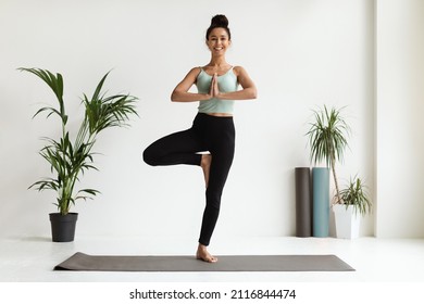 Life Balance. Young Beautiful Woman Practicing Yoga, Doing Tree Pose While Training On Fitness Mat In Modern Light Studio, Happy Millennial Female In Activewear Standing On One Leg With Hands Clasped - Powered by Shutterstock