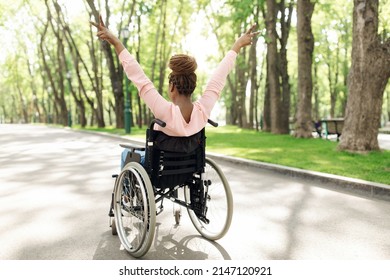 Life is beautiful. Full length of millennial black woman in wheelchair enjoying walk in city park, showing peace gesture with both hands, back view. Copy space. Freedom concept - Shutterstock ID 2147120921