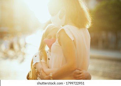 Life During Covid-19 Pandemic. Young Mother And Child With Masks And Yellow Backpack Hugging Outside.