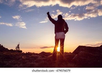 Life goals concept. Woman holding his fist in the air against a beautiful sunset.