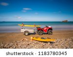 Life guard red quad bike and yellow surf board on the beach