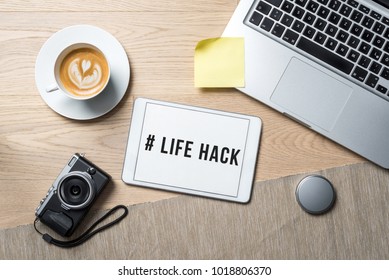 # Life hack writing on tablet with camera, coffee mug and laptop lying on photography office desk as flat lay