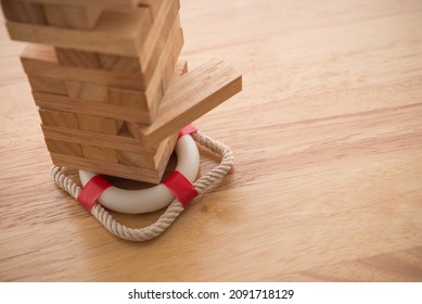 Life, health and property insurance business concept. Insurance is risk control management plan. Lifebuoy support under wooden block tower stacking game on wooden table background with copy space.