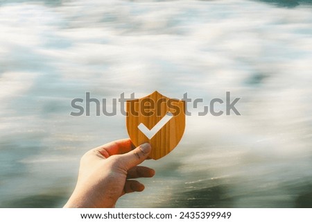 Life insurance businessman with bang holding wooden shield symbol with check mark with a background of fast-flowing water, it indicates an uncertain future.