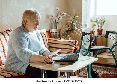 Life Insurance, Disability Medical Insurance Policy For Seniors. Mature Woman In Glasses With Laptop And Documents On The Background Of Rollator Mobility Walker For Seniors At Home