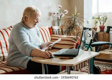 Life Insurance, Disability Medical Insurance Policy For Seniors. Mature Woman In Glasses With Laptop And Documents On The Background Of Rollator Mobility Walker For Seniors At Home