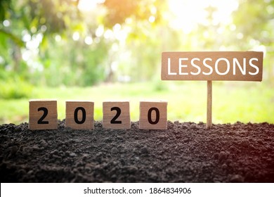 Life lessons and learnings from the year 2020 concept. A tree branch with a single remaining last leaf hanging beside a 2020 learning in wooden blocks at sunset. 