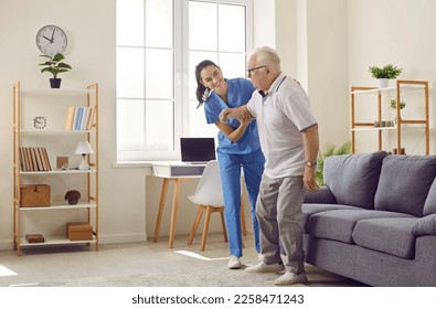 Life of pensioner in modern specialized nursing home. Friendly young female caregiver who cares for elderly man in nursing home helps him get up from sofa. Elderly care concept. Side view. - Powered by Shutterstock