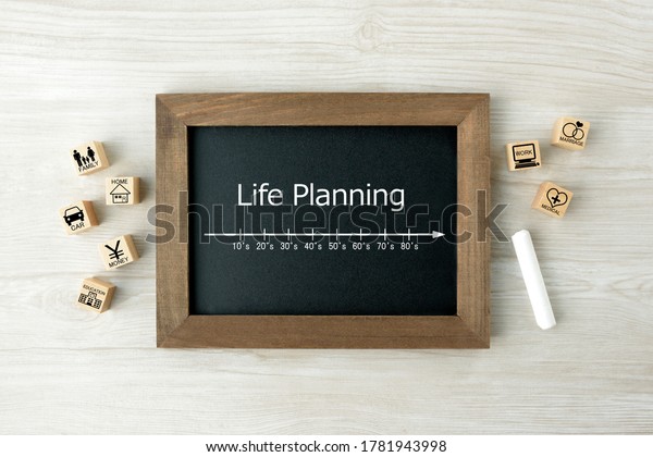 Life planning scale on blackboard and wooden\
blocks with house events\
pictogram
