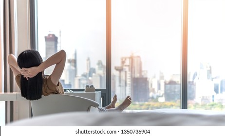 Life Quality Concept With Young Woman Relaxing And Resting In Comfort Business Hotel Guest Room Or Luxury Home Living Room Looking Toward Beautiful City View Of Cityscape