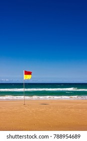 A Life Saver Flag Stands Alone On A Beach At Gold Coast, Queensland, Australia. It's Safe To Swim Between The Flags, But The Beach Seems To Be Quite Empty.