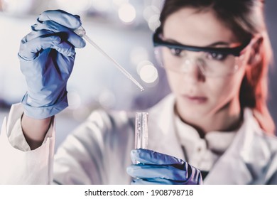 Life scientists researching in laboratory. Focused female life science professional pipetting solution into the glass cuvette. Lens focus on researcher's eyes. Healthcare and biotechnology concept. - Powered by Shutterstock