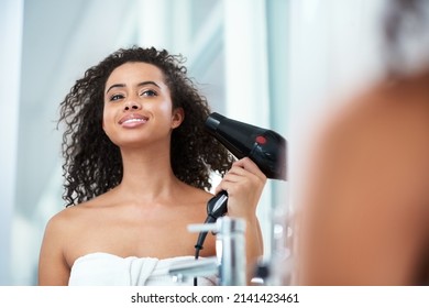 Life is too short to have boring hair. Shot of an attractive young woman blowdrying her hair at home.
