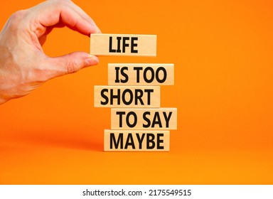 Life is short for maybe symbol. Concept words Life is too short to say maybe on wooden blocks on a beautiful orange table orange background. Businessman hand. Business motivational life maybe concept.