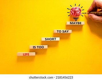 Life is short for maybe symbol. Concept words Life is too short to say maybe on wooden blocks on a beautiful yellow table yellow background. Businessman hand. Business motivational life maybe concept.
