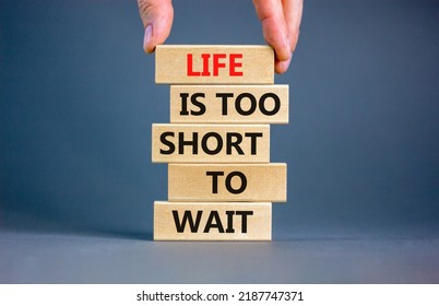 Life is short to wait symbol. Concept words Life is too short to wait on wooden blocks on a beautiful grey table grey background. Businessman hand. Business motivational life or wait concept.