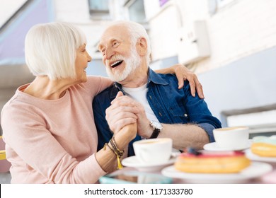 Life together. Low angle of cheerful senior couple holding hands and laughing - Powered by Shutterstock