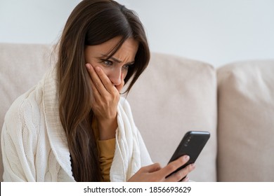 Life Troubles, Break Up With Boyfriend, Bad News, Heartbreak. Worried Woman Sitting On Couch Holds Mobile Phone Read Message Unpleasant Sms Cover Mouth With Hand Feels Upset, Crying. 