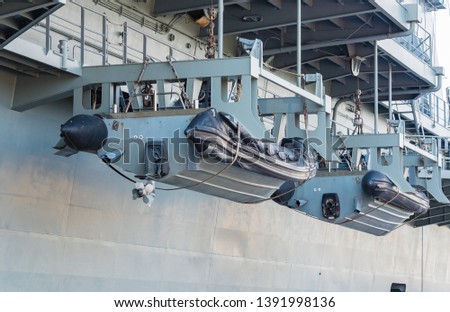 Lifeboat hanging on battle ship at port.