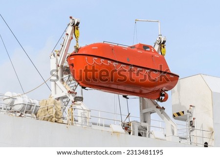 Lifeboat on big cargo vessel. Lowering orange lifeboat to water. Abandon ship drill. Lifeboat training. Man over board drill. Lifeboat training.