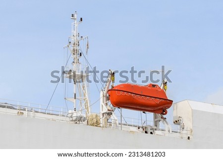 Lifeboat on big cargo vessel. Lowering orange lifeboat to water. Abandon ship drill. Lifeboat training. Man over board drill. Lifeboat training.