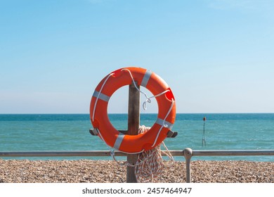 lifebouy, orange lifebouy by a beach and sea with blue sky - Powered by Shutterstock