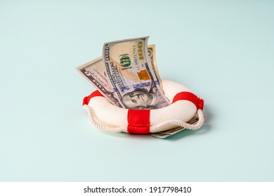 A lifebuoy with banknotes lie on a blue background, the concept of assistance and security in finance - Shutterstock ID 1917798410