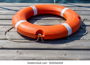 The lifebuoy is lying on a wooden pier. The concept of saving drowning on the water. - Powered by Shutterstock